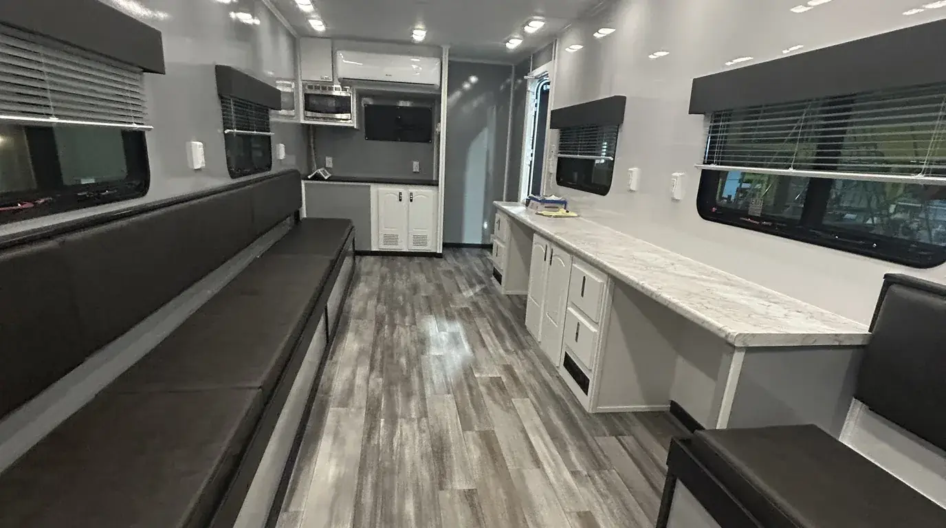 Inside a break room trailer with bench seating, tables, refrigerator and air conditioning